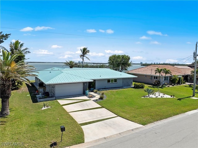 view of front facade with concrete driveway, a garage, a front yard, and metal roof