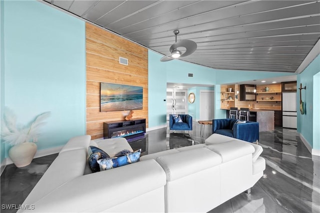 living room featuring visible vents, lofted ceiling, wooden walls, and baseboards