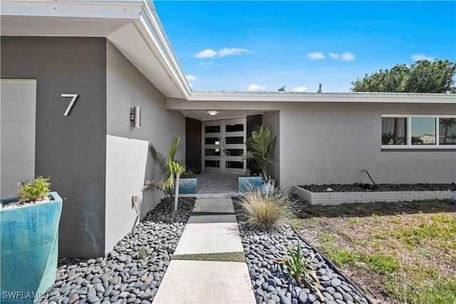 property entrance with stucco siding and french doors