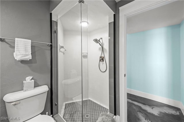 bathroom with a shower stall, toilet, and baseboards