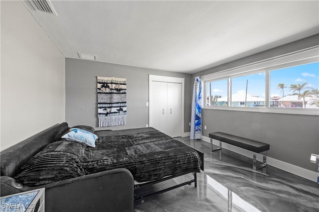 bedroom with a closet, visible vents, finished concrete flooring, and baseboards