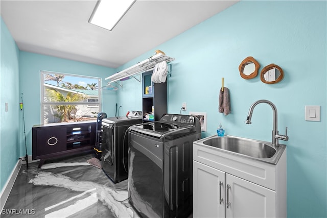 laundry room with cabinet space, washing machine and dryer, baseboards, and a sink