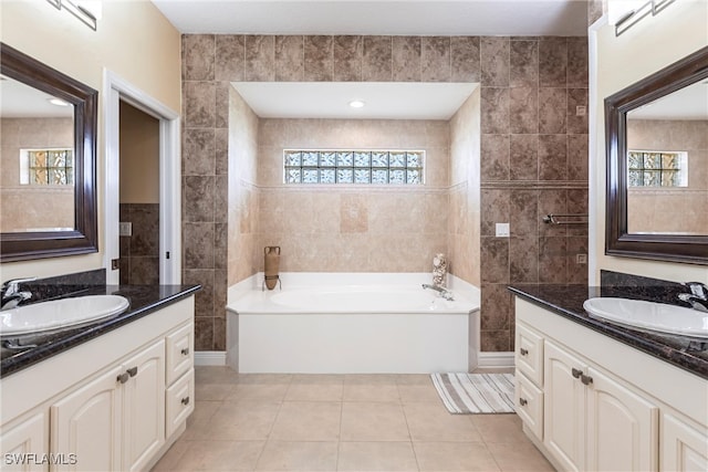 bathroom featuring tile patterned flooring, tile walls, a bath, and a sink