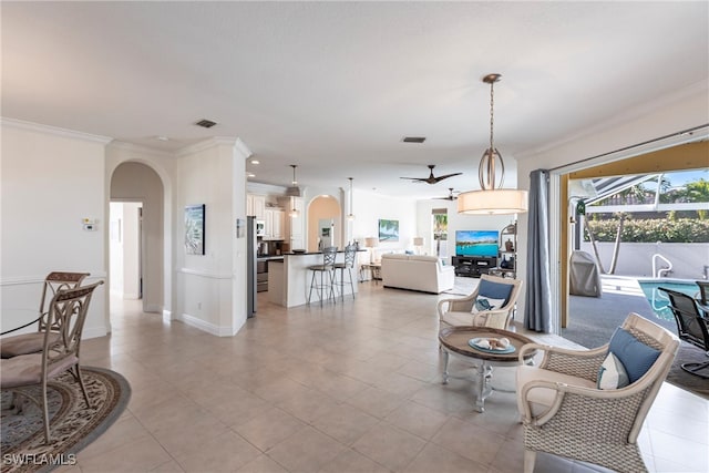 living room with visible vents, arched walkways, a ceiling fan, and crown molding