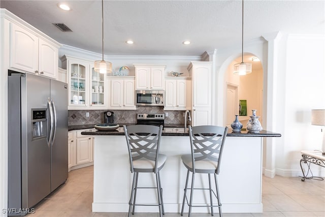 kitchen with dark countertops, visible vents, backsplash, appliances with stainless steel finishes, and arched walkways