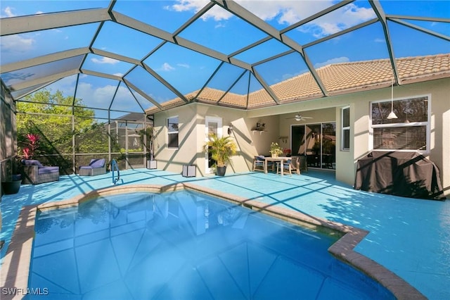 pool with a patio area, glass enclosure, and a ceiling fan