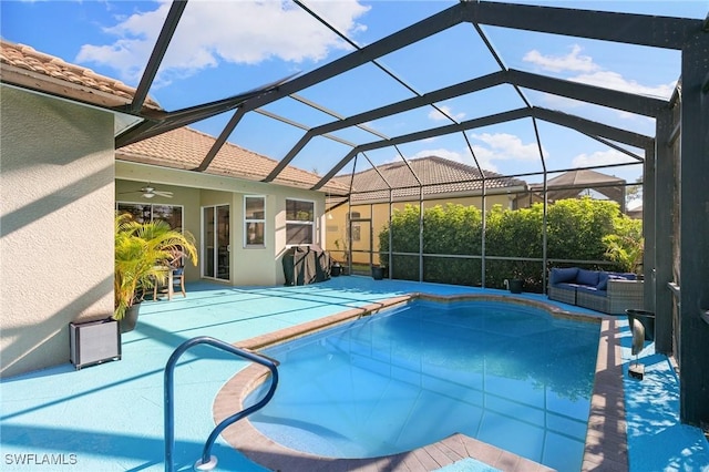 pool featuring glass enclosure, ceiling fan, a patio area, and an outdoor hangout area