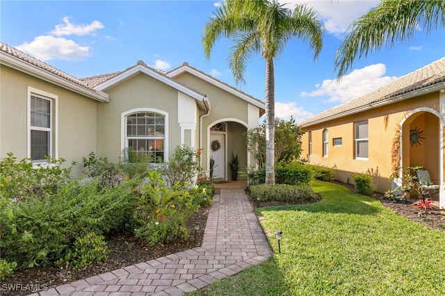 property entrance featuring a yard and stucco siding