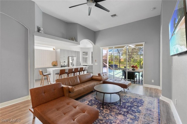 living area with baseboards, visible vents, light wood finished floors, and ceiling fan