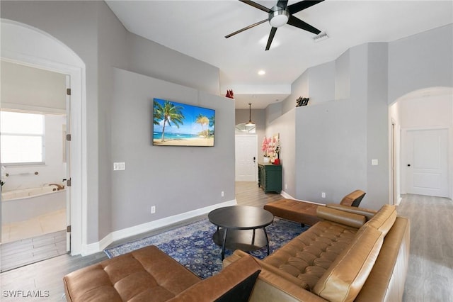 living room with visible vents, baseboards, wood finished floors, arched walkways, and a ceiling fan