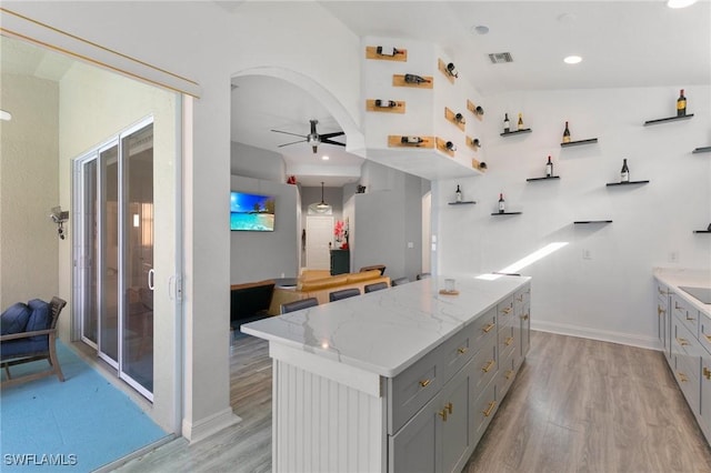 kitchen with visible vents, light wood-style flooring, gray cabinets, ceiling fan, and a center island