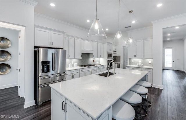 kitchen featuring a center island with sink, premium range hood, a sink, ornamental molding, and stainless steel appliances