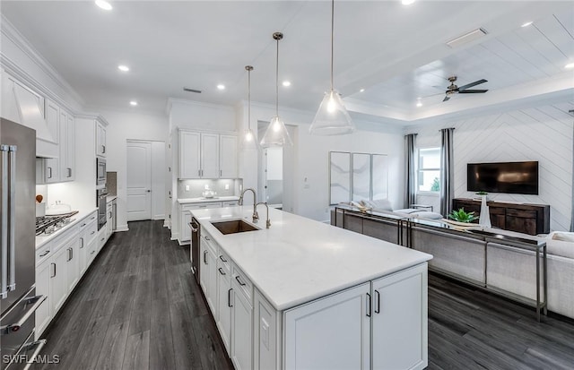 kitchen featuring a kitchen island with sink, a sink, light countertops, white cabinetry, and open floor plan