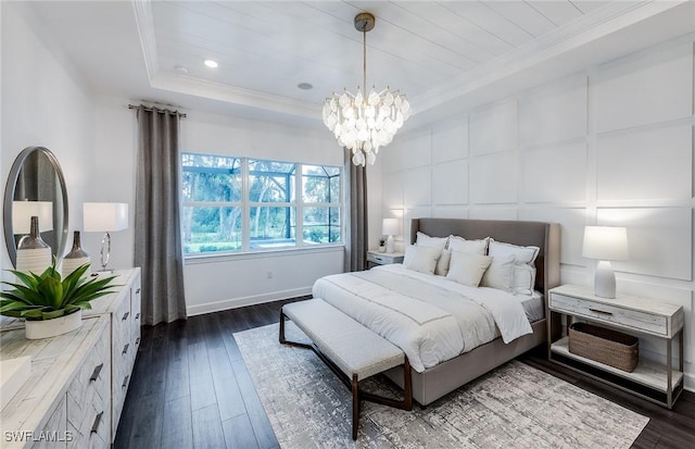 bedroom featuring a tray ceiling, a decorative wall, dark wood-style floors, and ornamental molding