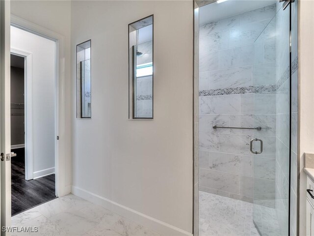 full bath featuring marble finish floor, a stall shower, and baseboards