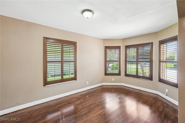 unfurnished room with dark wood finished floors and baseboards