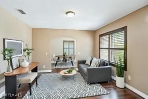 living area with baseboards, visible vents, and wood finished floors