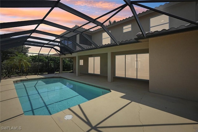 pool at dusk with a patio, a lanai, and an outdoor pool