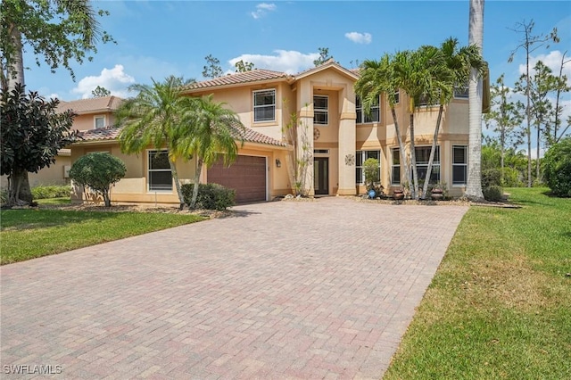 mediterranean / spanish home featuring a tiled roof, decorative driveway, an attached garage, a front yard, and stucco siding
