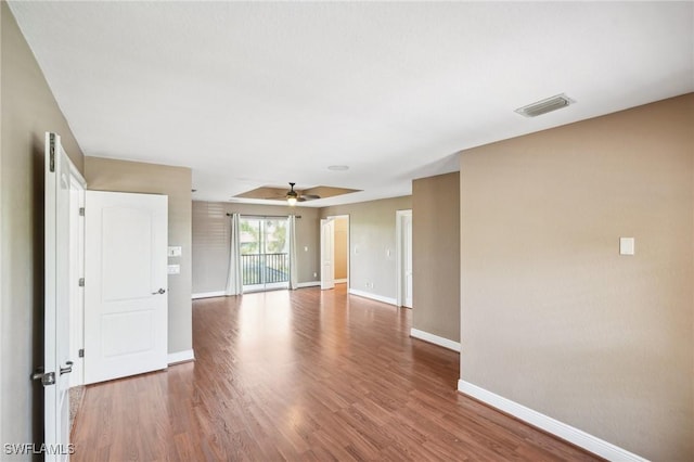 unfurnished room featuring baseboards, ceiling fan, visible vents, and wood finished floors