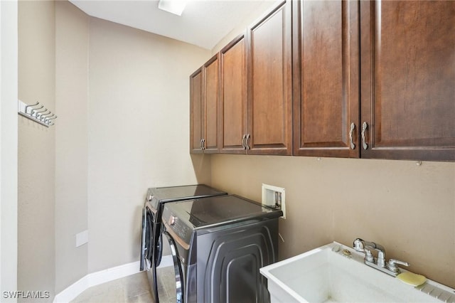 laundry room with a sink, cabinet space, baseboards, and washer and dryer