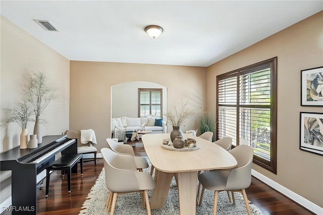 dining room featuring arched walkways, dark wood-style floors, baseboards, and visible vents