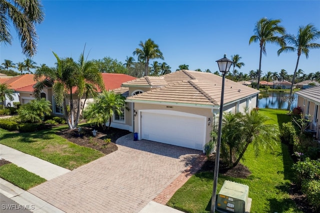 view of front of home with a tiled roof, a front yard, stucco siding, decorative driveway, and a garage