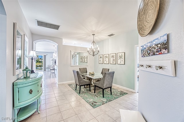 dining space featuring light tile patterned floors, visible vents, baseboards, arched walkways, and a notable chandelier