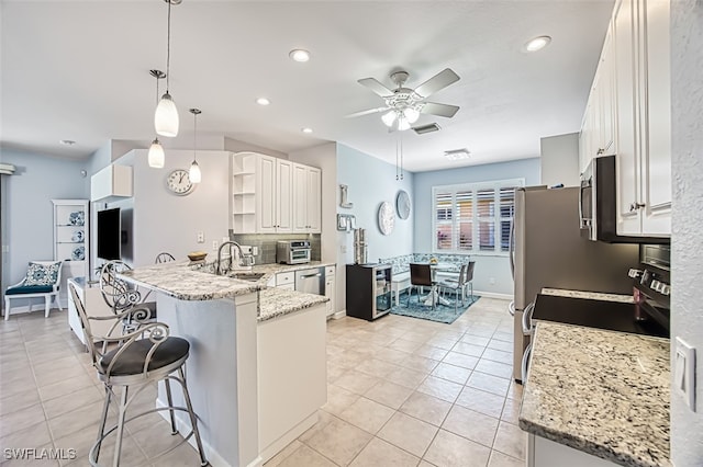 kitchen with open shelves, ceiling fan, a breakfast bar, a peninsula, and a sink