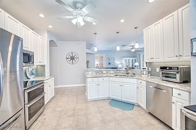 kitchen featuring a peninsula, a sink, ceiling fan, white cabinets, and appliances with stainless steel finishes