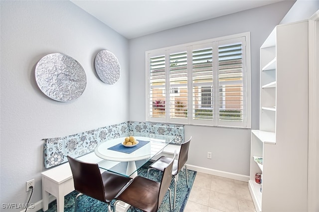 tiled dining room featuring breakfast area and baseboards