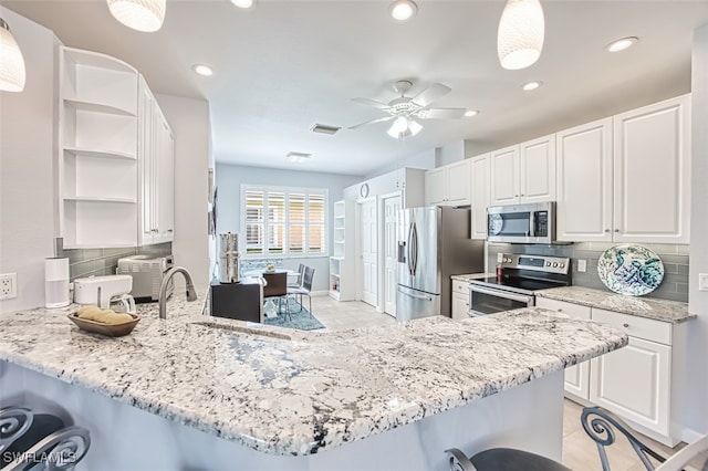 kitchen featuring visible vents, open shelves, a peninsula, stainless steel appliances, and a kitchen bar