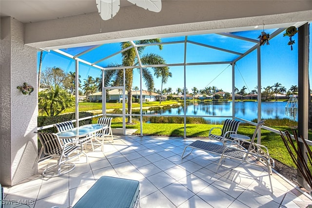 view of patio / terrace featuring glass enclosure, a ceiling fan, and a water view