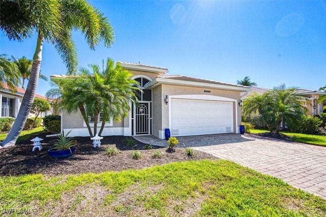 view of front of home featuring decorative driveway, an attached garage, and stucco siding