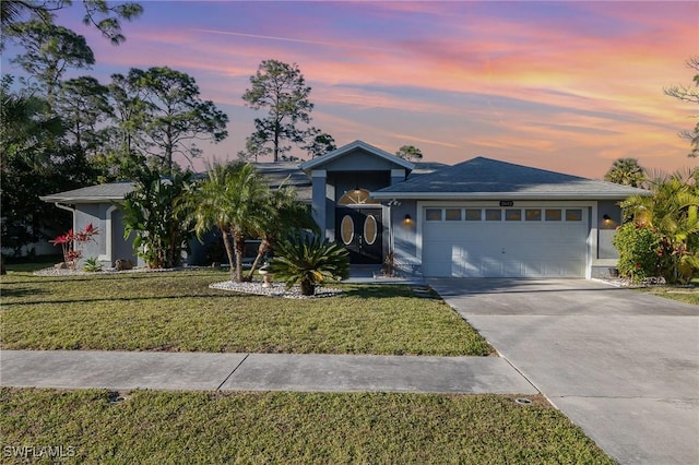 single story home with stucco siding, driveway, an attached garage, and a yard