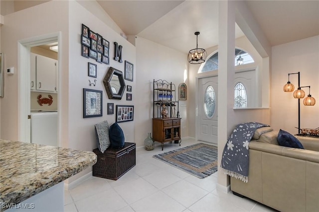 entrance foyer with a chandelier, light tile patterned floors, and baseboards