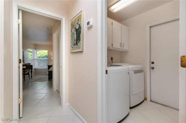 laundry area featuring light tile patterned floors, baseboards, cabinet space, and washer and clothes dryer