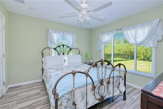 bedroom featuring visible vents, multiple windows, and light wood-style floors