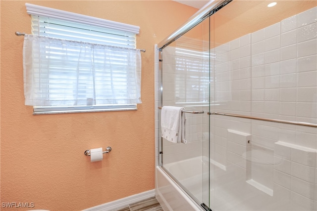 full bathroom featuring baseboards and shower / bath combination with glass door