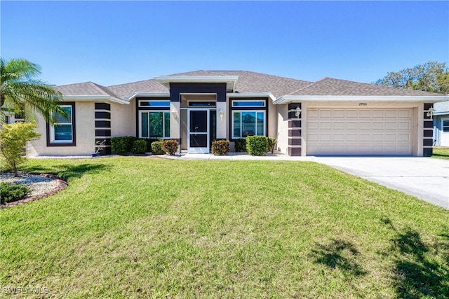 prairie-style house featuring stucco siding, concrete driveway, a garage, and a front yard