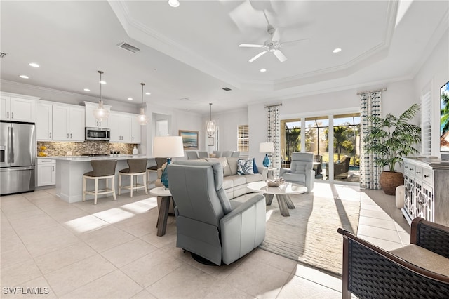 living room featuring light tile patterned floors, a tray ceiling, ceiling fan, and crown molding