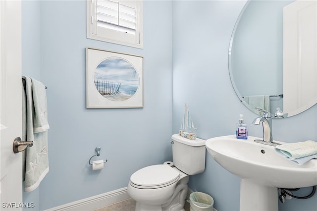 half bathroom with a sink, baseboards, and toilet