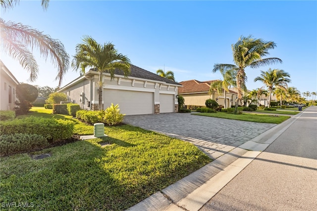 view of front facade with stucco siding, decorative driveway, stone siding, a front yard, and a garage