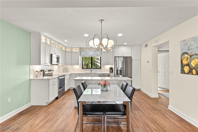 dining area with a notable chandelier, recessed lighting, baseboards, and light wood finished floors