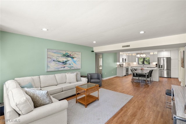 living area featuring visible vents, recessed lighting, an inviting chandelier, light wood finished floors, and baseboards