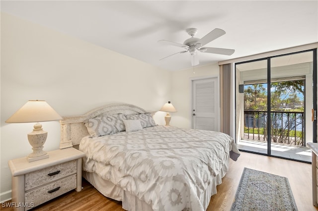 bedroom featuring a ceiling fan, access to outside, wood finished floors, and expansive windows