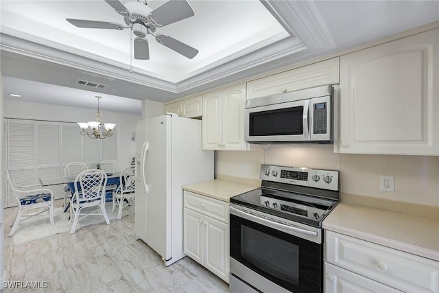 kitchen with a tray ceiling, stainless steel appliances, visible vents, and ornamental molding