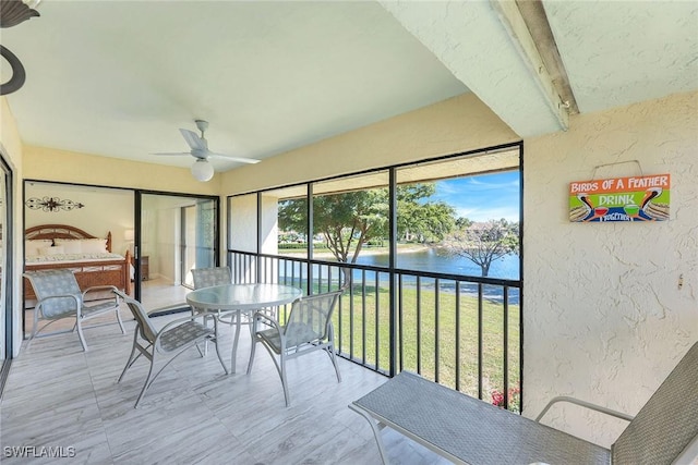 sunroom / solarium with a water view and a ceiling fan