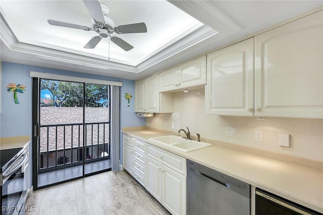 kitchen featuring ceiling fan, light countertops, a tray ceiling, stainless steel appliances, and a sink