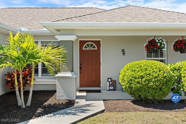 property entrance with stucco siding and roof with shingles